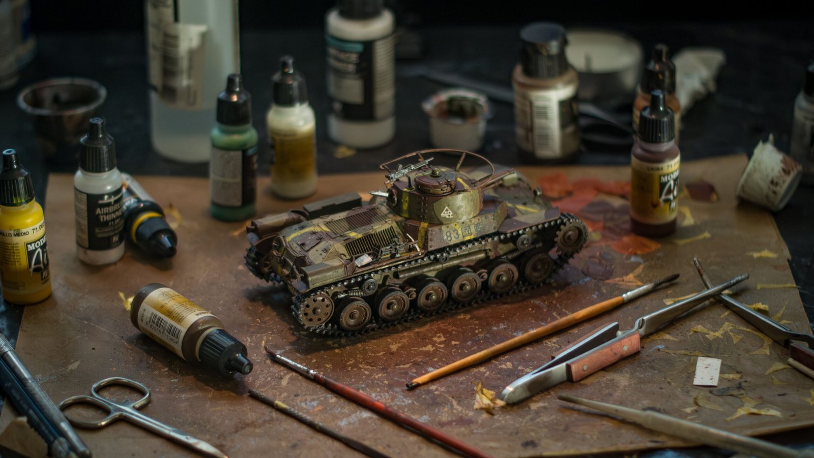High-quality model tank surrounded by various painting supplies for a realistic diorama.
